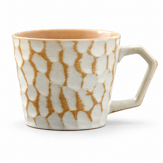Ivory ceramic coffee mug with ochre markings and angular handle on a white background