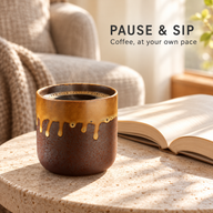 Keramik-Kaffeetasse ohne Henkel mit Kaffee neben einem aufgeschlagenen Buch auf einem Steintisch