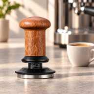 Samovyrovnávací tamper na espresso s dřevěnou rukojetí na kamenné lince vedle šálku espressa