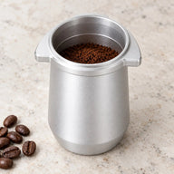 計量前のコーヒー粉を入れたシルバーの54mmドージングカップ