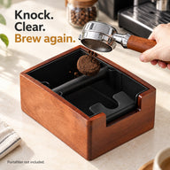 Ein Espresso-Puck wird aus einem Siebträger in den Abschlagbehälter aus Akazienholz geklopft.