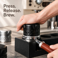 Tamper espresso à ressort noir pressé dans un porte-filtre sur une station de tassage