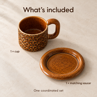 One amber floral ceramic cup and one matching saucer displayed separately