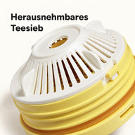 Nahaufnahme des herausnehmbaren weißen Teesiebs unter dem gelben Deckel