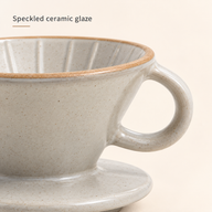 Close-up of speckled cream ceramic glaze, tan rim and loop handle