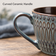 Close-up of the embossed ceramic coffee cup's curved loop handle
