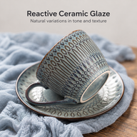 Reactive glaze ceramic coffee cup tilted on its matching saucer to show the foot ring