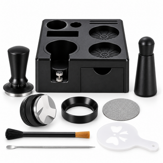 Black nine-piece espresso tool set with square storage station, tamper, WDT tool in holder, distributor, funnel, puck screen, brush, latte art needle and stencil on white.