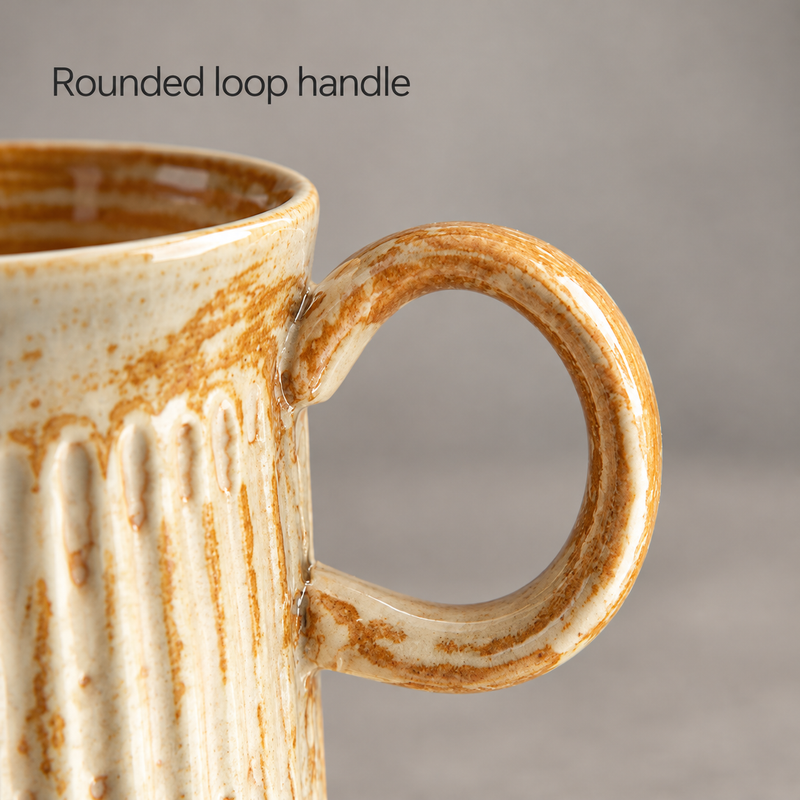 Close-up of the amber and cream ceramic cup's rounded loop handle
