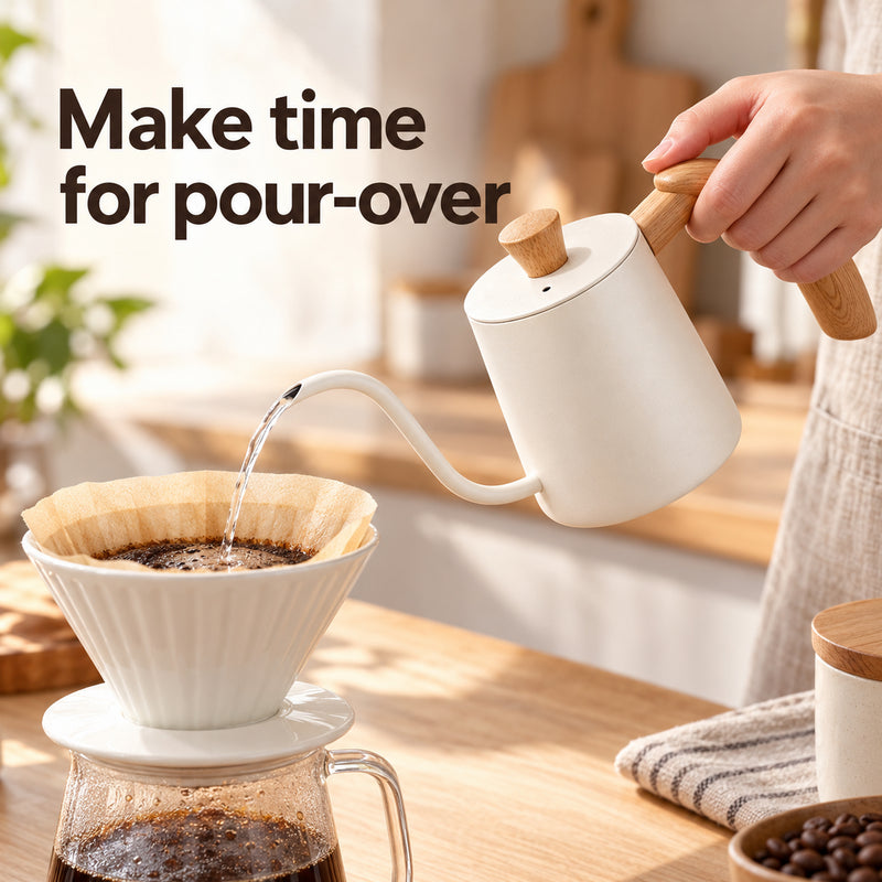 Ivory white gooseneck kettle pouring water into a paper-lined coffee dripper in a home kitchen.