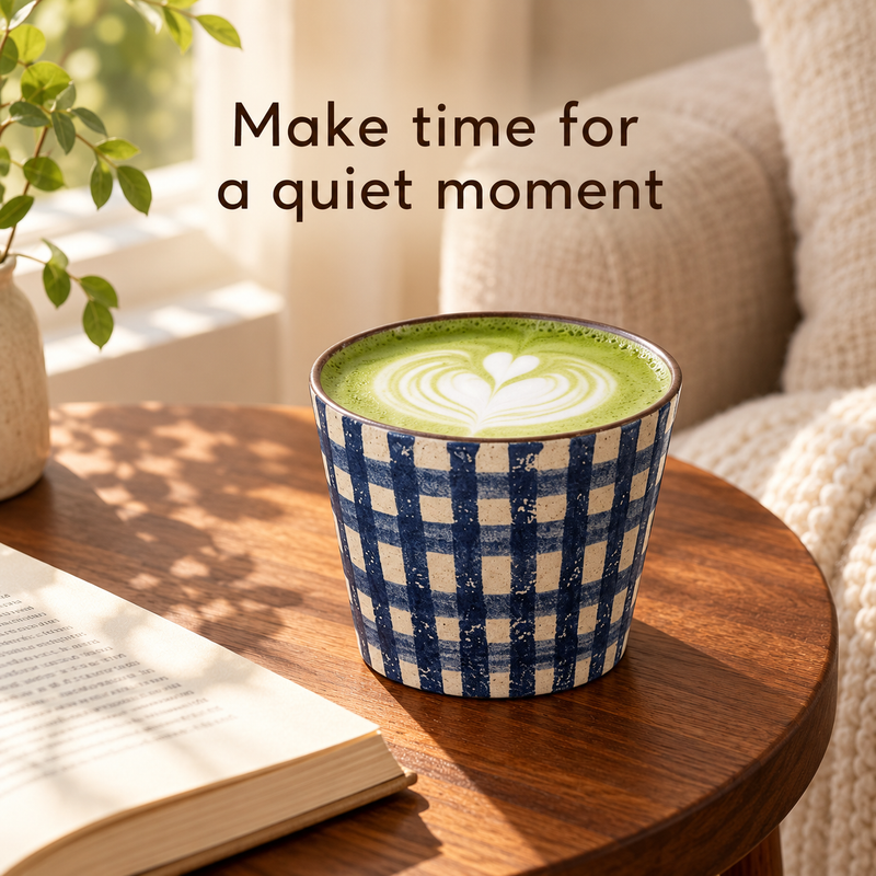 Blue and ivory gingham ceramic cup filled with matcha latte beside a book