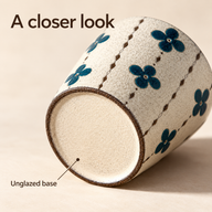 Teal Blossom ceramic cup on its side showing the pale unglazed base and narrow brown foot ring.