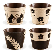 Vier ontwerpen van keramische koffiekoppen zonder oor op een witte achtergrond: Ivoren bladeren, Ivoren bloemen, Zwart botanisch en Tweekleurige bloemen.