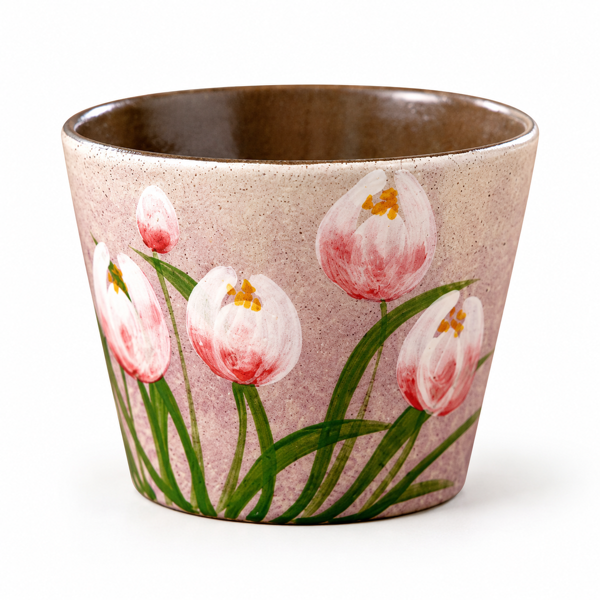 Keramische koffiekop zonder oor met roze-witte tulp, groene bladeren en bruin geglazuurde binnenkant op een witte achtergrond.