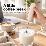 Ivory cordless milk frother used in a glass of milk on a bright home desk