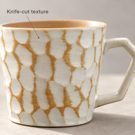 Primo piano della texture sfaccettata e delle linee ocra sulla tazza in ceramica avorio