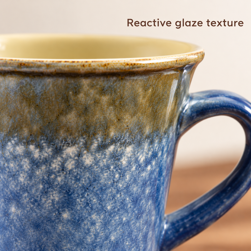 Close-up of the mottled blue and olive-brown reactive glaze on the ceramic mug