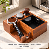 Wood espresso tamping station beside a home espresso machine with a portafilter, distributor and tamper for demonstration only; coffee tools not included.