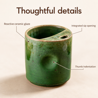 Green ceramic cup with callouts identifying reactive glaze, thumb indentation and integrated sip opening.