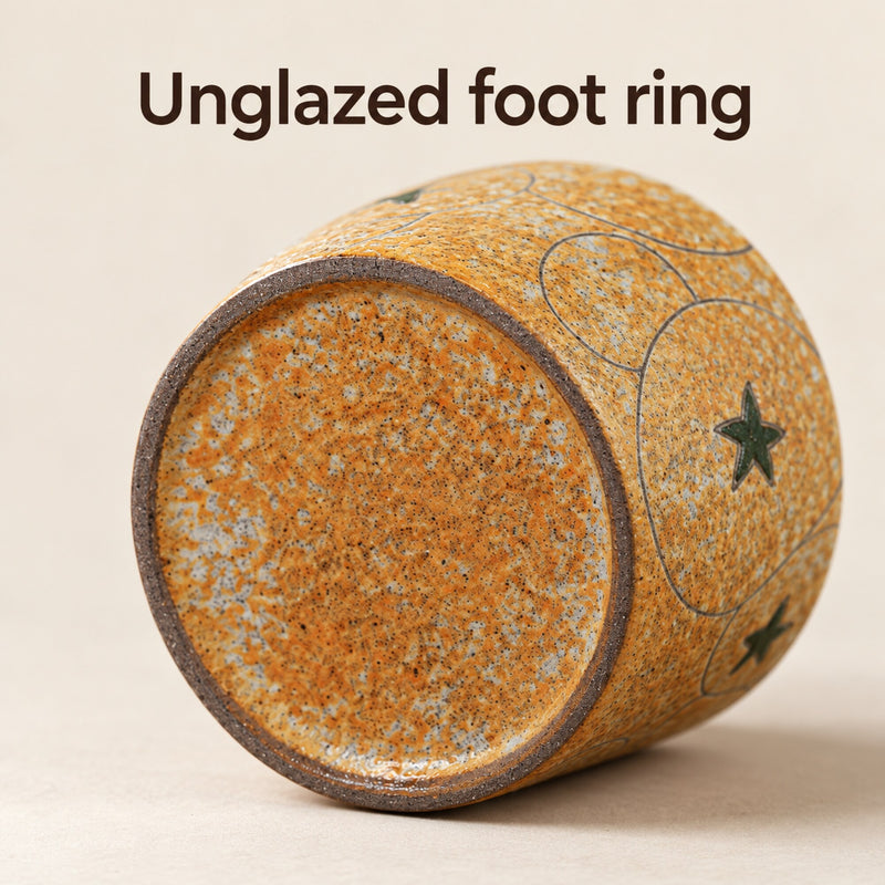 Fondo della tazza in ceramica con base ambra puntinata circondata da un anello d'appoggio scuro non smaltato.