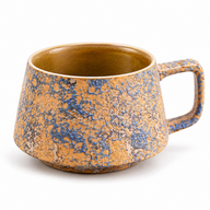 Blue and ochre textured ceramic coffee mug with a squared handle on a white background