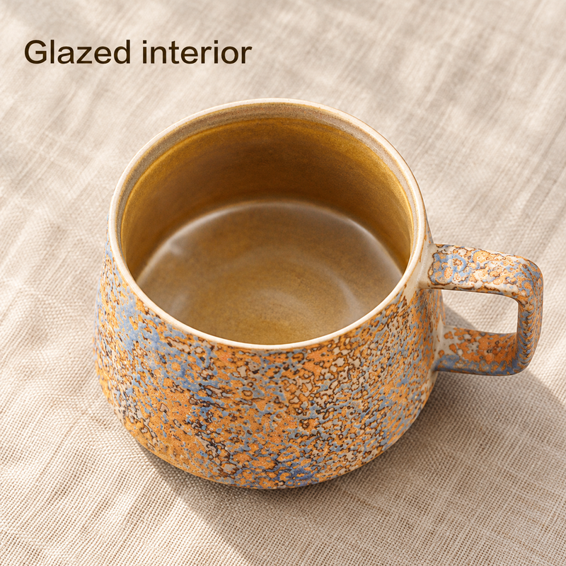 Overhead view of the brown-gold glazed interior and squared handle of a blue and ochre mug