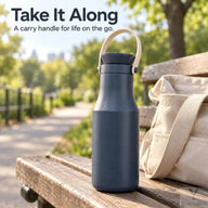 Navy insulated bottle with carry handle on a park bench beside a bag