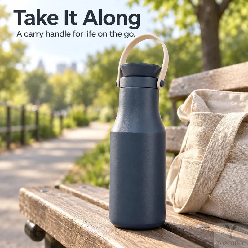 Navy insulated bottle with carry handle on a park bench beside a bag