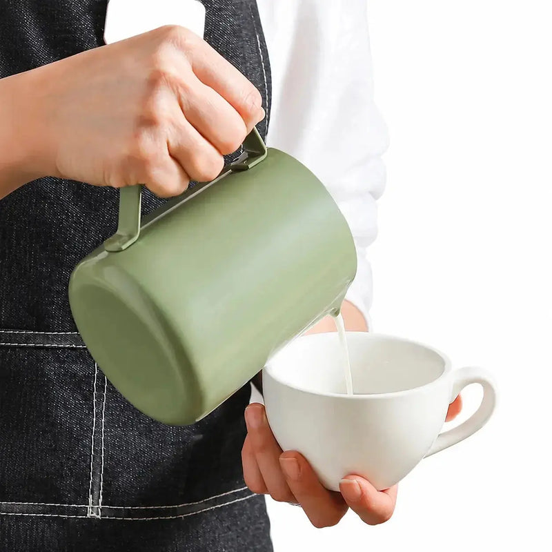 Pichet à dégradé vert versant du lait chauffé à la vapeur dans une tasse