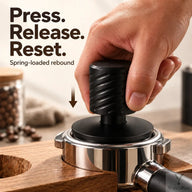 Black espresso tamper being pressed vertically into a supported portafilter