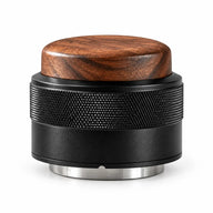 Black espresso distributor and tamper with walnut wood top, diamond-knurled body and stainless steel base on a white background