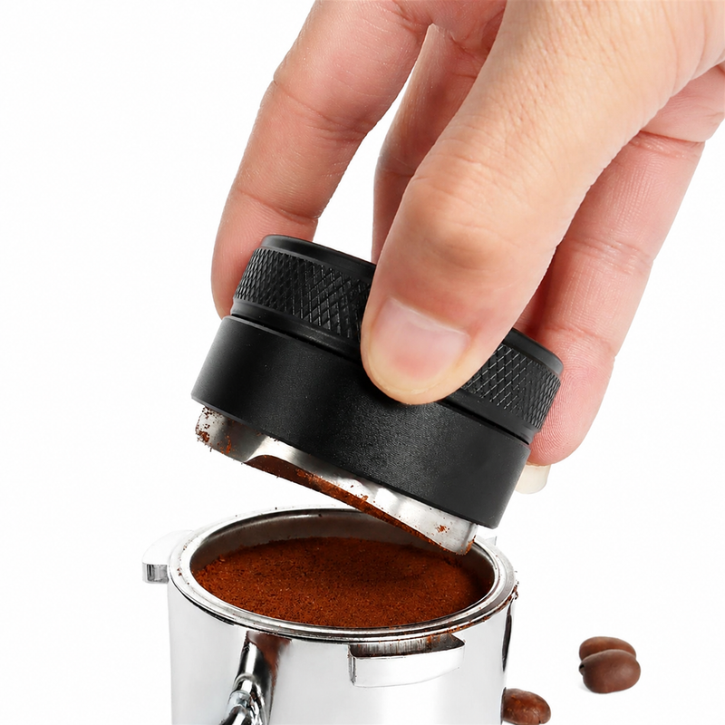 Hand using the Yozcoffee black 3-leaf espresso distributor over a portafilter filled with coffee grounds