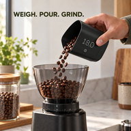 Measured coffee beans poured from weighing cup into grinder