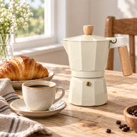 Cream moka pot and coffee on a sunlit breakfast table