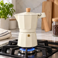 Cream moka pot brewing on a gas stove