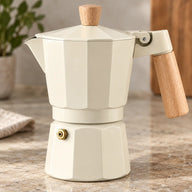 Cream moka pot showing wood-look handle and brass-colored safety valve