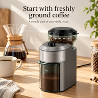 Electric burr coffee grinder on an oak kitchen counter beside pour-over coffee