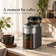 Compact gray coffee grinder in a workspace coffee corner with a ceramic cup