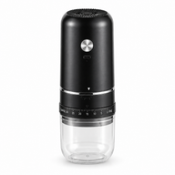 Black Yozcoffee electric coffee grinder with silver button and clear grounds cup on a white background