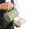 Yozcoffee green gradient milk frothing pitcher pouring milk into a cup