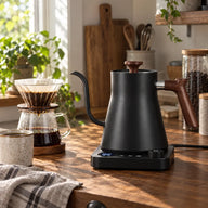 Black Yozcoffee electric gooseneck kettle beside a pour-over coffee brewer