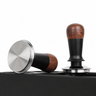 Two angles of the Yozcoffee walnut wood constant force espresso tamper on an espresso station