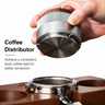 Hand holding the silver espresso distributor over a portafilter, showing the concentric leveling base from below